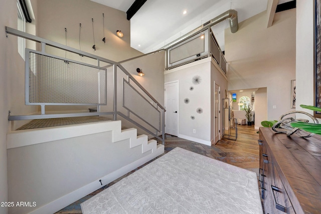 staircase featuring a towering ceiling and baseboards