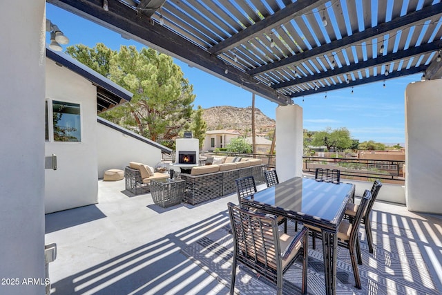 view of patio featuring a mountain view, an outdoor living space with a fireplace, a pergola, and fence