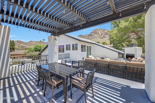 view of patio / terrace featuring a mountain view, an outdoor living space with a fireplace, a pergola, and outdoor dining area