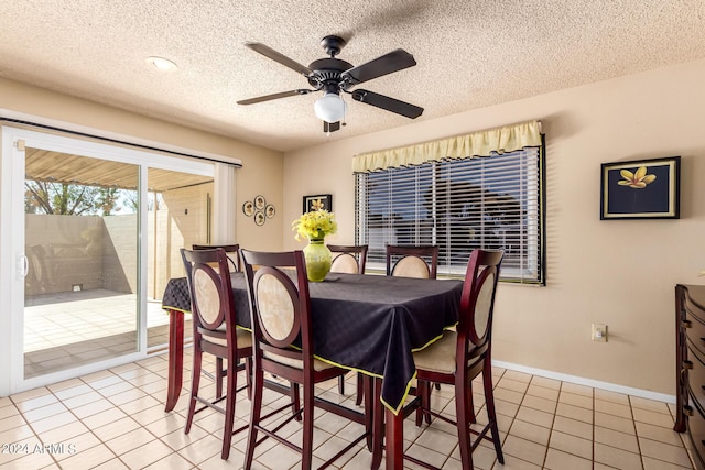 dining room with baseboards, a ceiling fan, light tile patterned flooring, and a textured ceiling