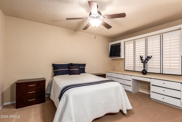 bedroom with light carpet, built in desk, a textured ceiling, and a ceiling fan