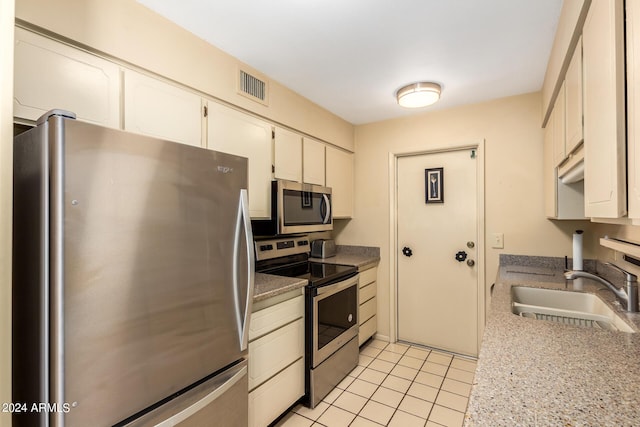 kitchen with light tile patterned flooring, white cabinets, visible vents, stainless steel appliances, and a sink