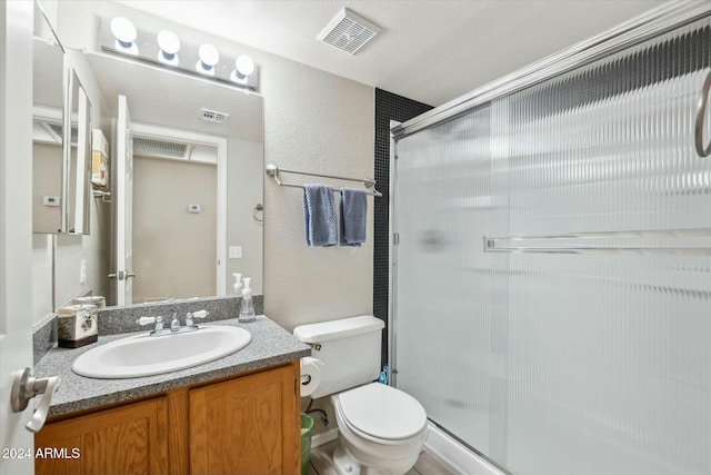 bathroom with vanity, a shower with shower door, and toilet