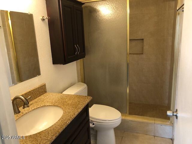 full bathroom with tile patterned flooring, a shower stall, toilet, and vanity