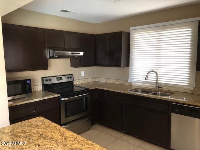 kitchen with visible vents, a sink, under cabinet range hood, appliances with stainless steel finishes, and light tile patterned floors