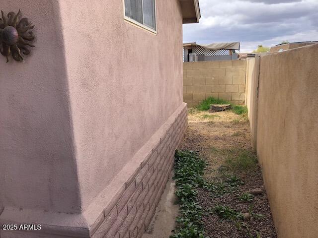 view of property exterior with stucco siding and fence