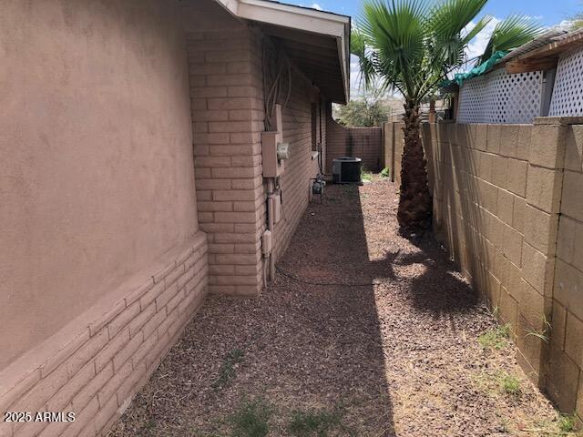 view of side of home featuring a fenced backyard, stucco siding, and central AC