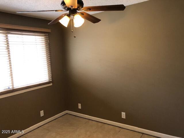 unfurnished room featuring baseboards and ceiling fan