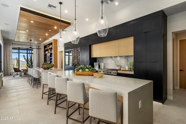 kitchen featuring a large island, modern cabinets, light countertops, pendant lighting, and backsplash