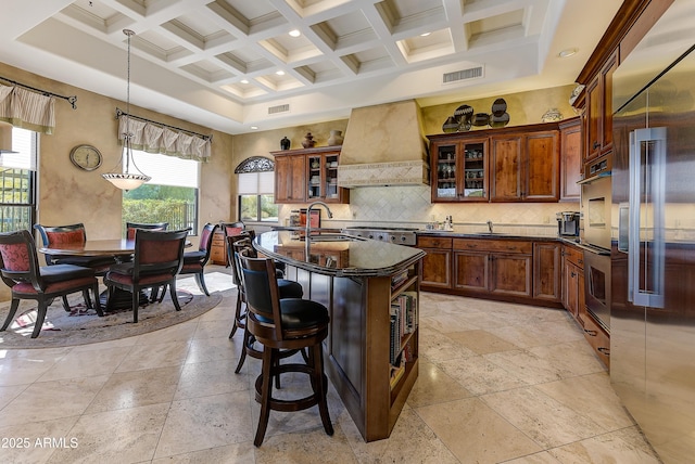 kitchen with beam ceiling, custom range hood, visible vents, backsplash, and a high ceiling