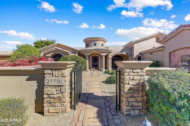 mediterranean / spanish house with a fenced front yard, a gate, a tiled roof, and stucco siding