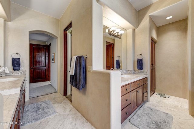 bathroom featuring a sink, two vanities, and an inviting chandelier