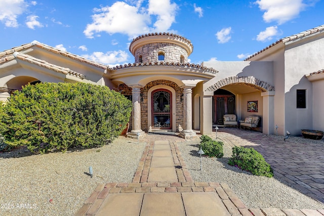 property entrance featuring stone siding, a tiled roof, and stucco siding