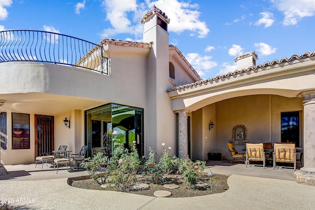 rear view of property with a patio, a balcony, and stucco siding