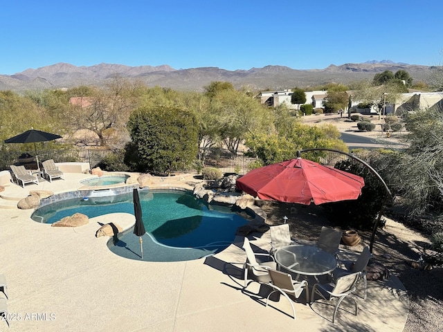 view of pool featuring a patio, a pool with connected hot tub, fence, and a mountain view