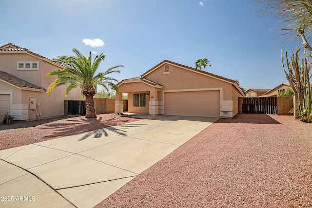 view of front of house with a garage, concrete driveway, a gate, fence, and stucco siding