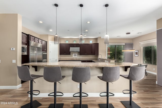 kitchen featuring dark brown cabinets, light wood-type flooring, built in appliances, and sink