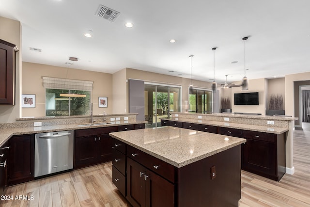 kitchen featuring stainless steel dishwasher, a kitchen island, sink, and light hardwood / wood-style flooring