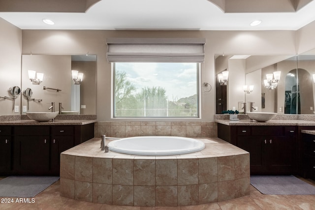 bathroom with tiled tub, vanity, and tile patterned flooring