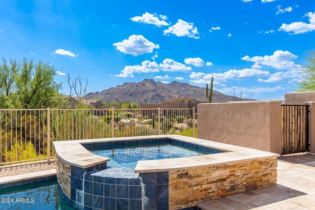 view of swimming pool with a mountain view and an in ground hot tub