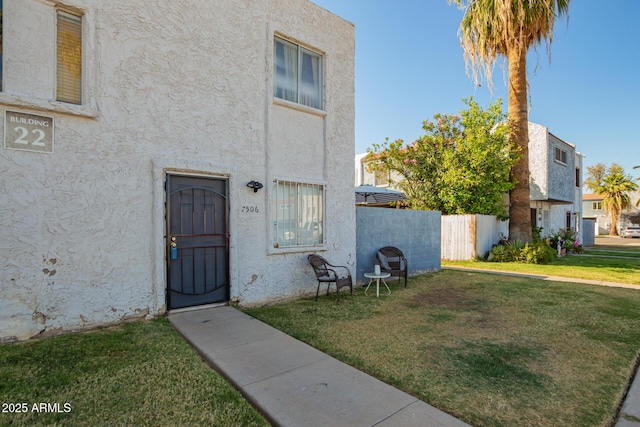7506 N 47th Dr, Glendale, AZ 85301 - view of exterior entry featuring a yard, stucco siding, and fence