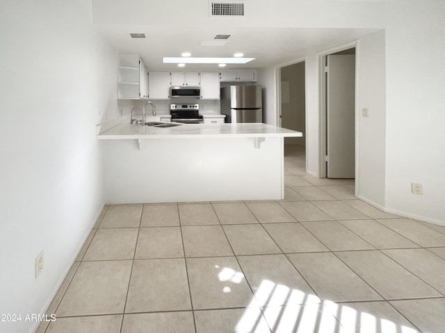 kitchen featuring white cabinets, sink, light tile patterned floors, appliances with stainless steel finishes, and kitchen peninsula