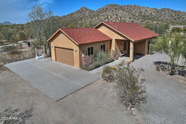 view of front of home featuring a garage, a shingled roof, a mountain view, and stucco siding