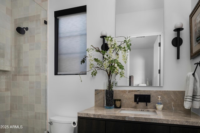 bathroom with tiled shower, toilet, and vanity