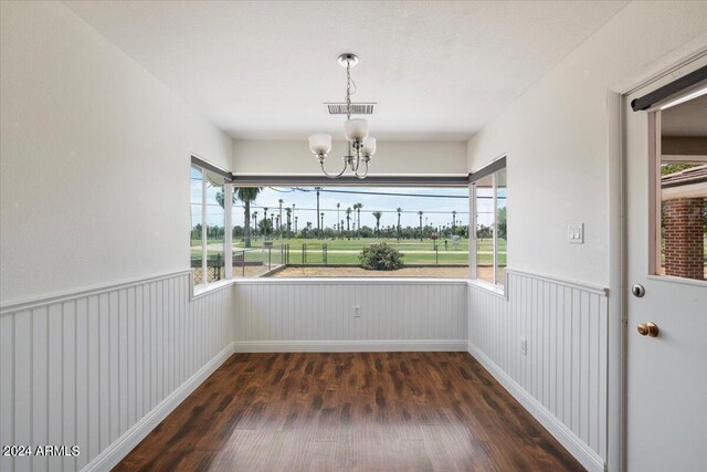 unfurnished dining area with an inviting chandelier and dark hardwood / wood-style floors