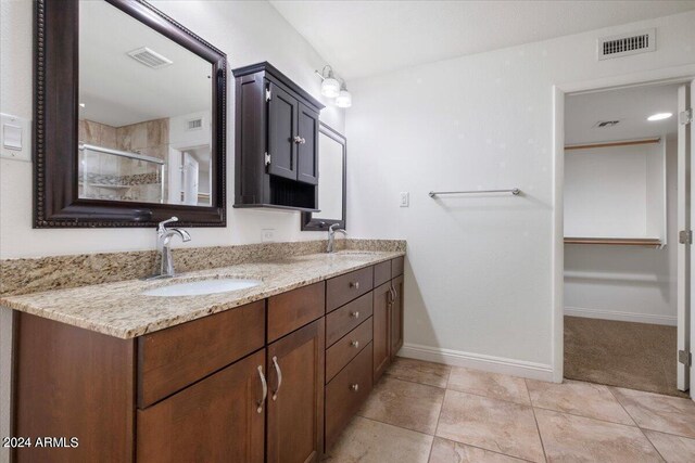 bathroom with tile patterned flooring, vanity, and walk in shower