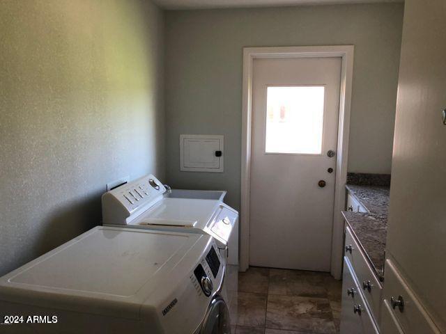 laundry room featuring independent washer and dryer, dark tile patterned floors, and cabinets