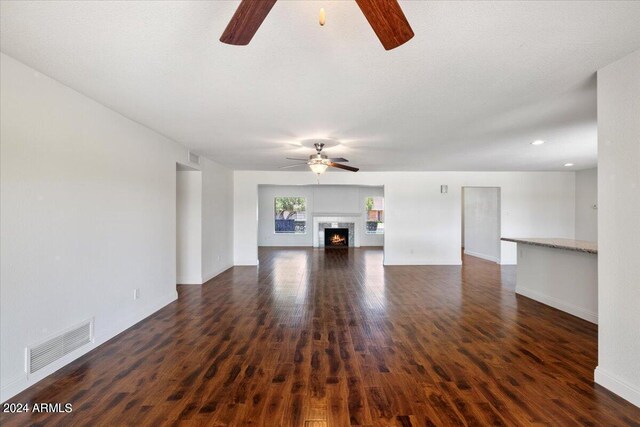 unfurnished living room featuring ceiling fan and dark hardwood / wood-style floors