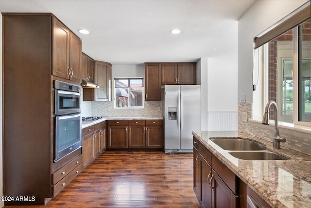 kitchen featuring backsplash, dark hardwood / wood-style flooring, light stone counters, sink, and stainless steel appliances