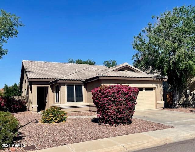 single story home featuring a garage, driveway, a tiled roof, and stucco siding