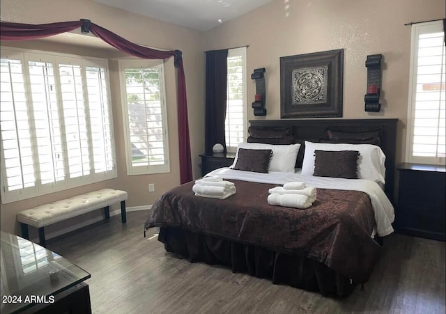 bedroom with lofted ceiling, baseboards, and wood finished floors