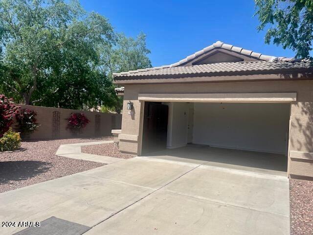 exterior space featuring driveway, stucco siding, fence, and a tiled roof