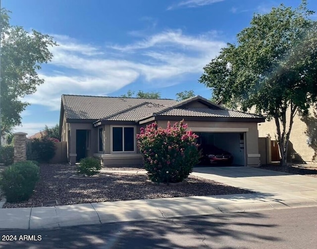 single story home featuring a garage, fence, a tiled roof, concrete driveway, and stucco siding