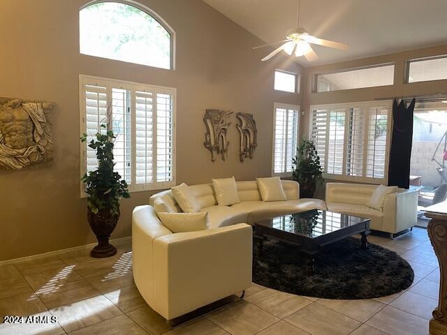 living area with light tile patterned floors, high vaulted ceiling, ceiling fan, and baseboards