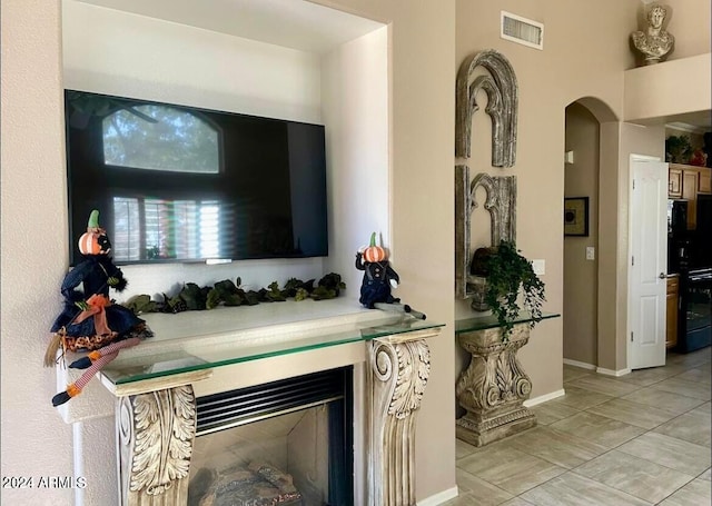 interior space featuring freestanding refrigerator, visible vents, baseboards, and light tile patterned floors