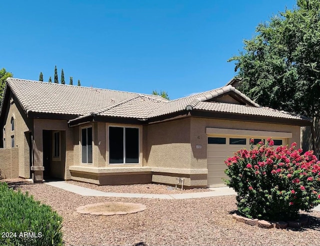 view of front of home with an attached garage, a tile roof, and stucco siding