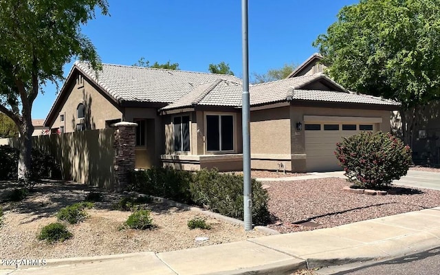 view of front of home featuring a garage, fence, a tile roof, and stucco siding