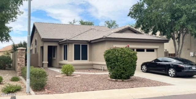 ranch-style home featuring a garage, driveway, a tiled roof, and stucco siding