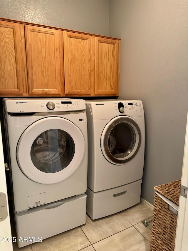 washroom with cabinet space, light tile patterned floors, and washer and dryer