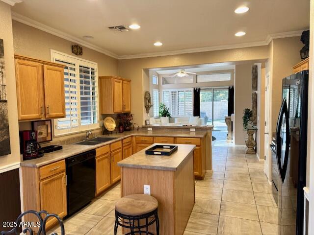 kitchen featuring visible vents, a breakfast bar, a center island, light countertops, and black appliances