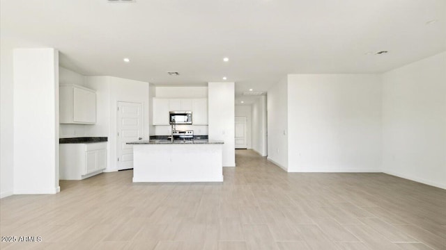 653 W Freedom St, Florence, AZ 85132 - kitchen featuring stainless steel microwave, open floor plan, dark countertops, recessed lighting, and an island with sink