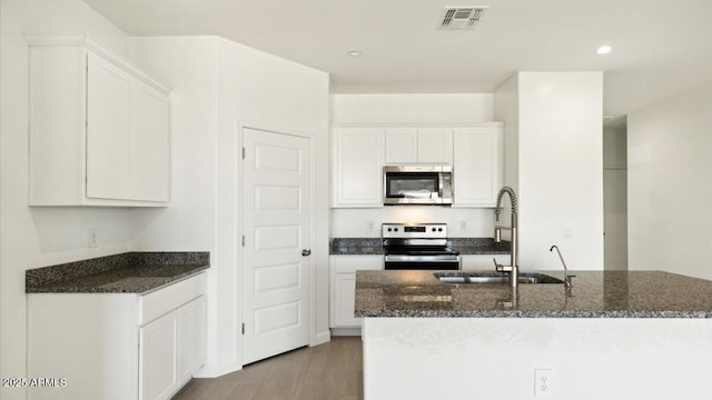 653 W Freedom St, Florence, AZ 85132 - kitchen with appliances with stainless steel finishes, dark stone counters, white cabinetry, recessed lighting, and a center island with sink