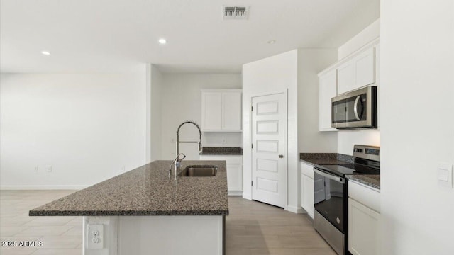 653 W Freedom St, Florence, AZ 85132 - kitchen with appliances with stainless steel finishes, a kitchen island with sink, white cabinets, recessed lighting, and dark stone countertops