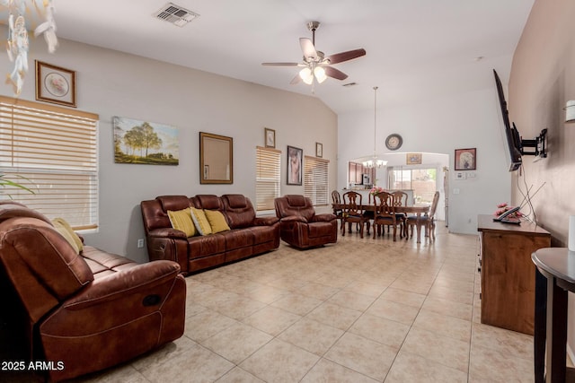 living room with ceiling fan, a chandelier, light tile patterned flooring, and high vaulted ceiling