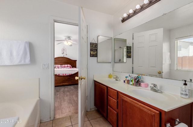 ensuite bathroom featuring tile patterned flooring, ceiling fan, double vanity, and a bath