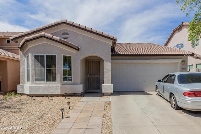 view of front facade featuring an attached garage, a tiled roof, driveway, and stucco siding